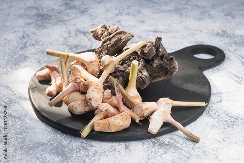 A variety of galangal rhizomes are showcased on a black cutting board, highlighting their distinct shapes and textures photo