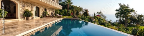 Lush greenery surrounds a large swimming pool overlooking the ocean, perfect for a relaxing day at the beach