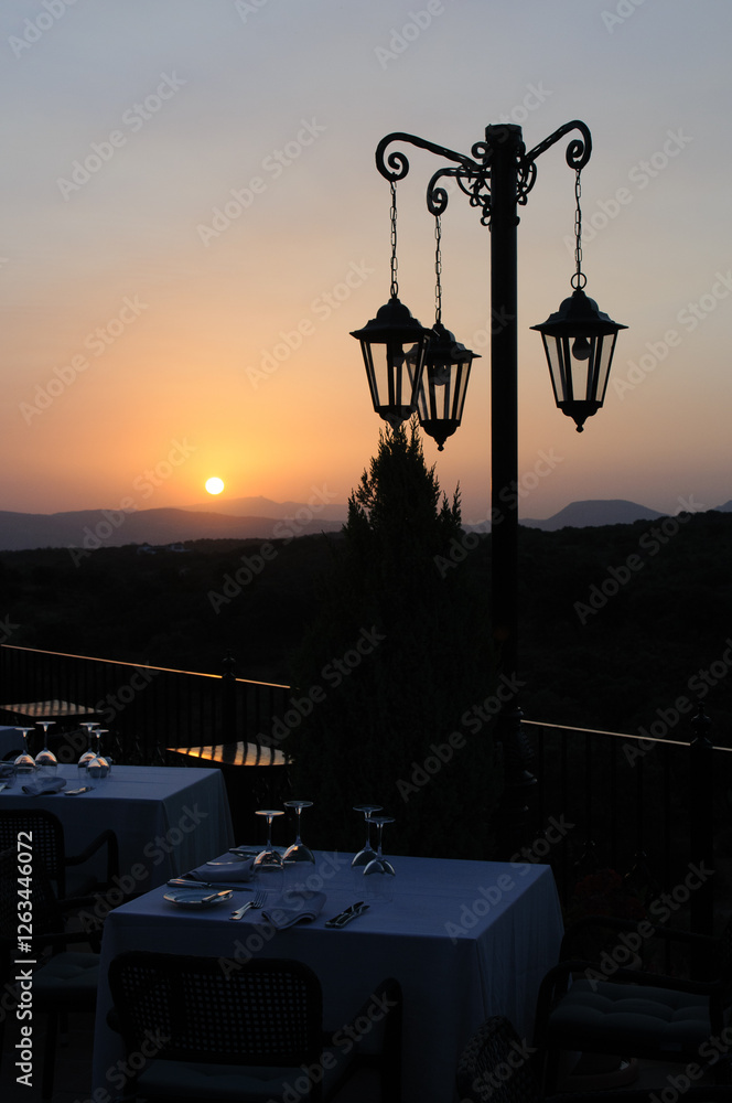 Elegantly set tables at a restaurant on a balcony overlooking the mountains of southern Spain at sunset. Elegantly set tables at a restaurant on a balcony overlooking the mountains of southern Spain at sunset.