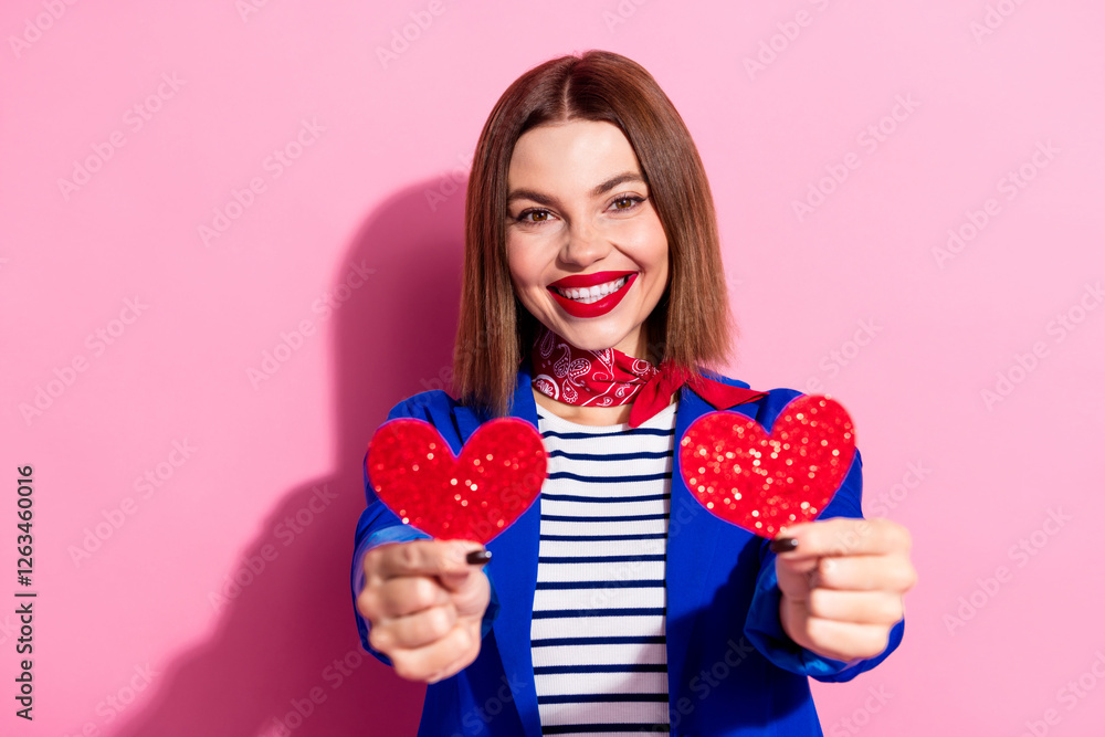 Stylish young woman holding two glittery red hearts against a pink background, dressed in elegant casual wear with bright accessories Stylish young woman holding two glittery red hearts against a pink background, dressed in elegant casual wear with bright accessories