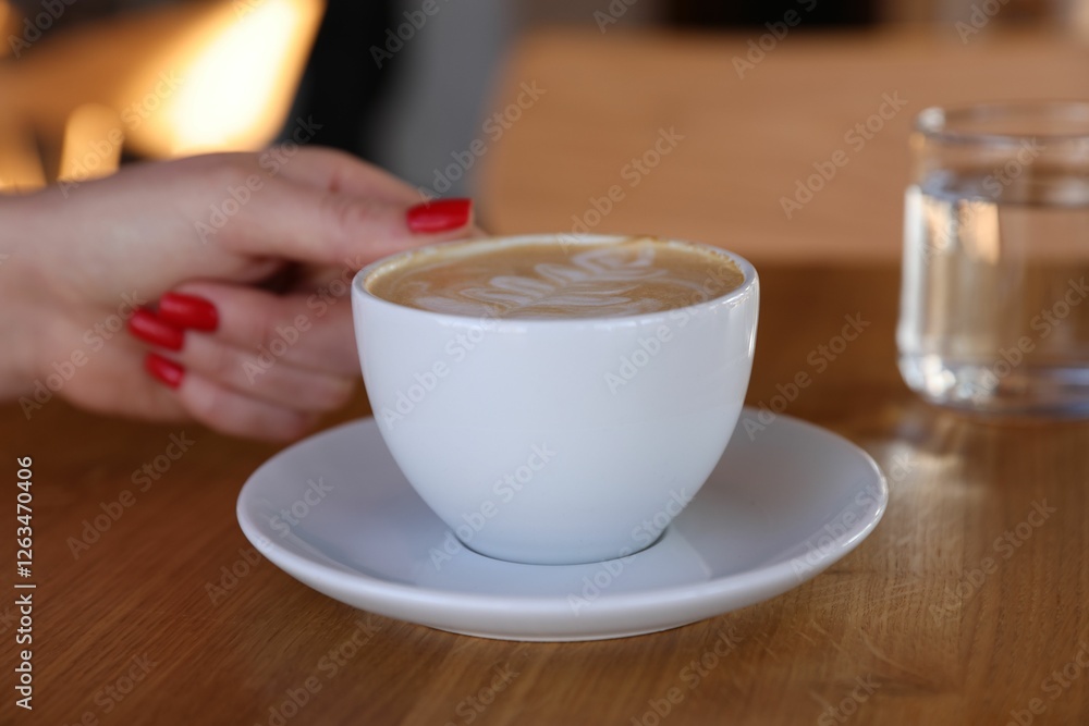 Woman with cup of aromatic coffee at wooden table in cafe, closeup Woman with cup of aromatic coffee at wooden table in cafe, closeup