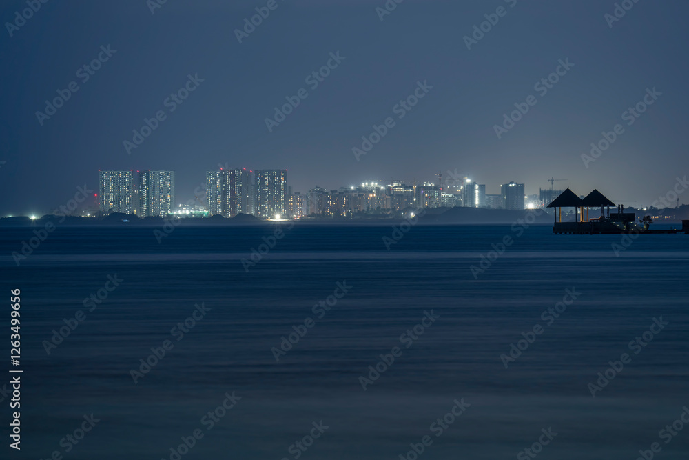Unique landscape about the Maldives. Capital city, Malé is on the background. Illuminated small rest place with bed on the foreground.