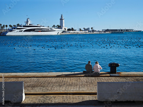 Pareja sentada en el muelle uno de Málaga photo