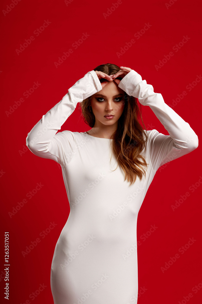 Girl with smokey eye makeup in a white silk dress, on a red background. Fashion pose.
