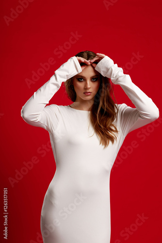 Obraz na płótnie Girl with smokey eye makeup in a white silk dress, on a red background. Fashion pose. w salonie