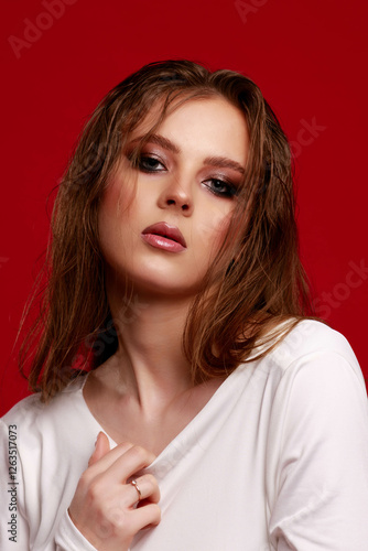 Obraz na płótnie Girl with smokey eye makeup in a white silk dress, on a red background. Fashion pose. w salonie