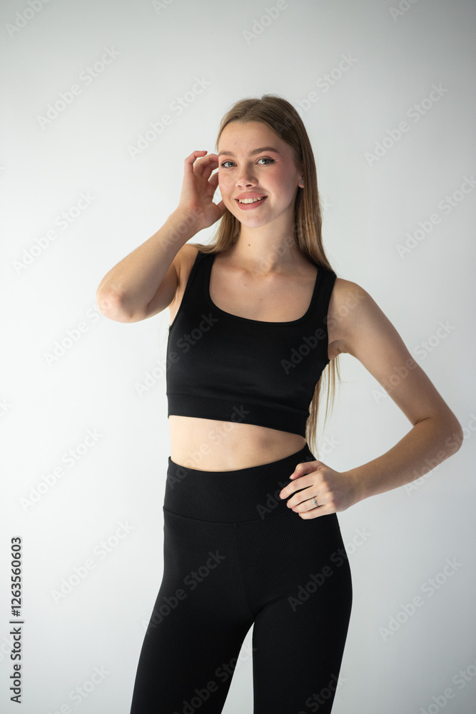 professional model in a sleek black outfit adjusts her jeans while gazing off-camera, showcasing her well-defined features and graceful body language professional model in a sleek black outfit adjusts her jeans while gazing off-camera, showcasing her well-defined features and graceful body language