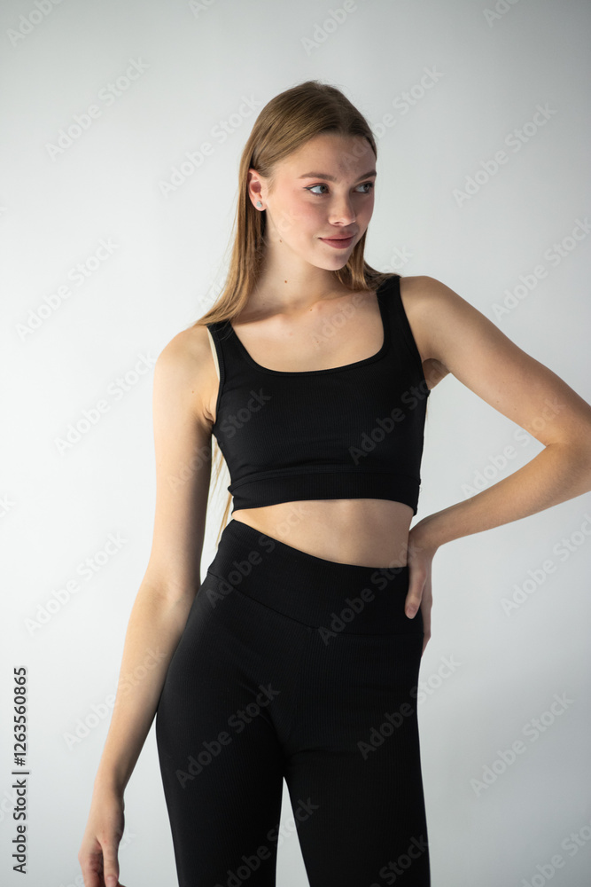 professional model in a sleek black outfit adjusts her jeans while gazing off-camera, showcasing her well-defined features and graceful body language professional model in a sleek black outfit adjusts her jeans while gazing off-camera, showcasing her well-defined features and graceful body language