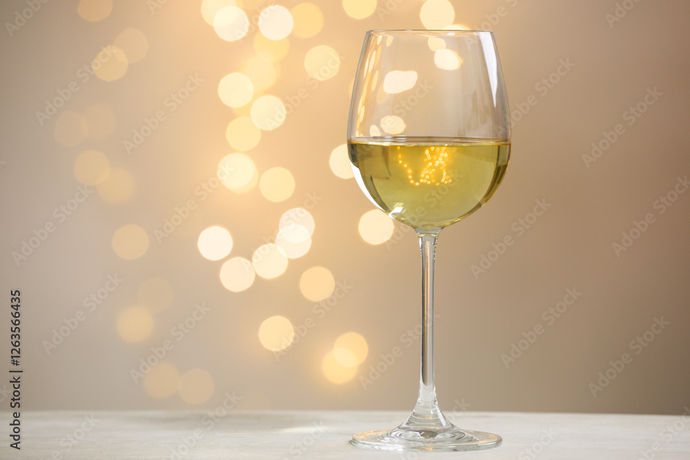 Tasty white wine in glass on table against grey background with blurred lights, bokeh effect. Space for text Tasty white wine in glass on table against grey background with blurred lights, bokeh effect. Space for text