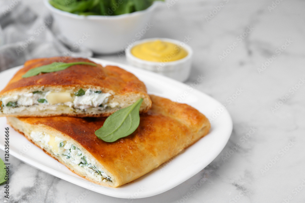 Pieces of tasty calzone with basil, cheese and sauce on white marble table, closeup. Space for text Pieces of tasty calzone with basil, cheese and sauce on white marble table, closeup. Space for text