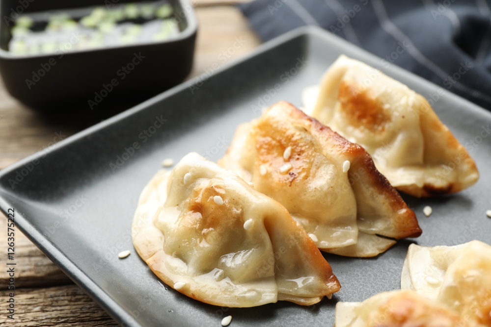 Fried gyoza dumplings with sesame seeds on wooden table, closeup Fried gyoza dumplings with sesame seeds on wooden table, closeup