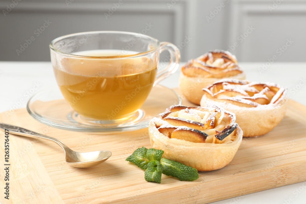 Freshly baked apple roses with mint and tea on white table, closeup Freshly baked apple roses with mint and tea on white table, closeup