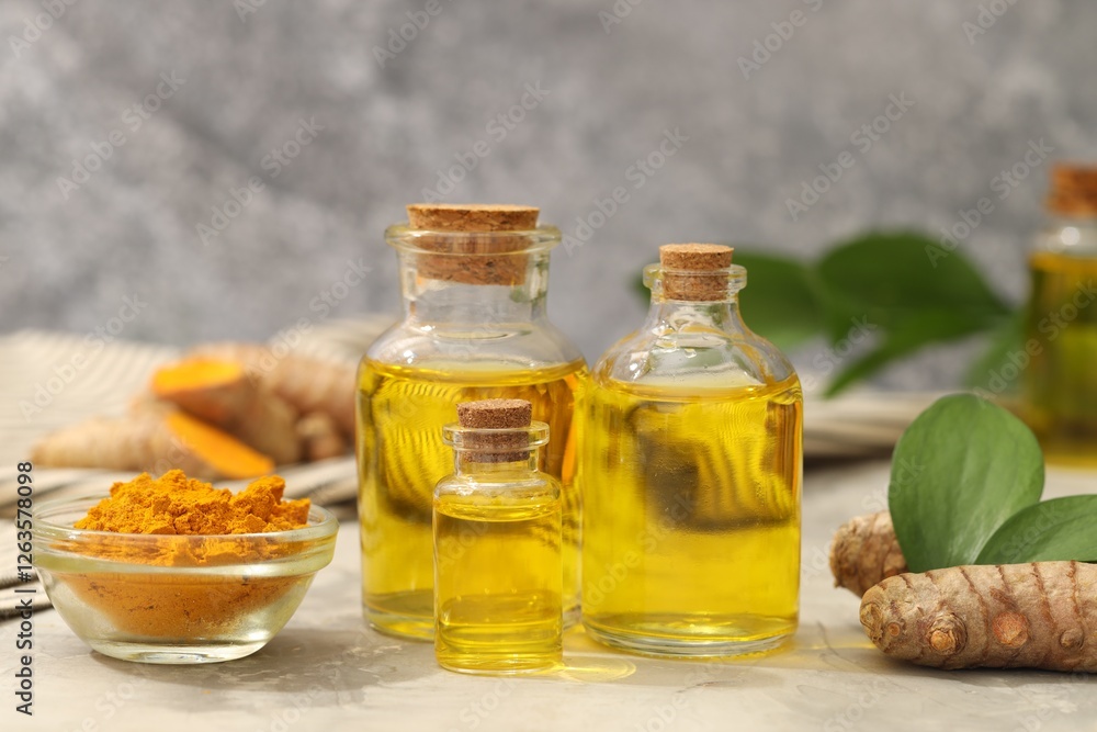 Turmeric oil, powder, roots and green leaves on grey table Turmeric oil, powder, roots and green leaves on grey table