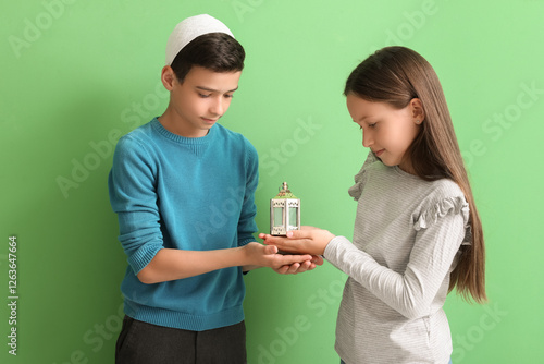 Little Muslim children with fanous lantern on green background photo