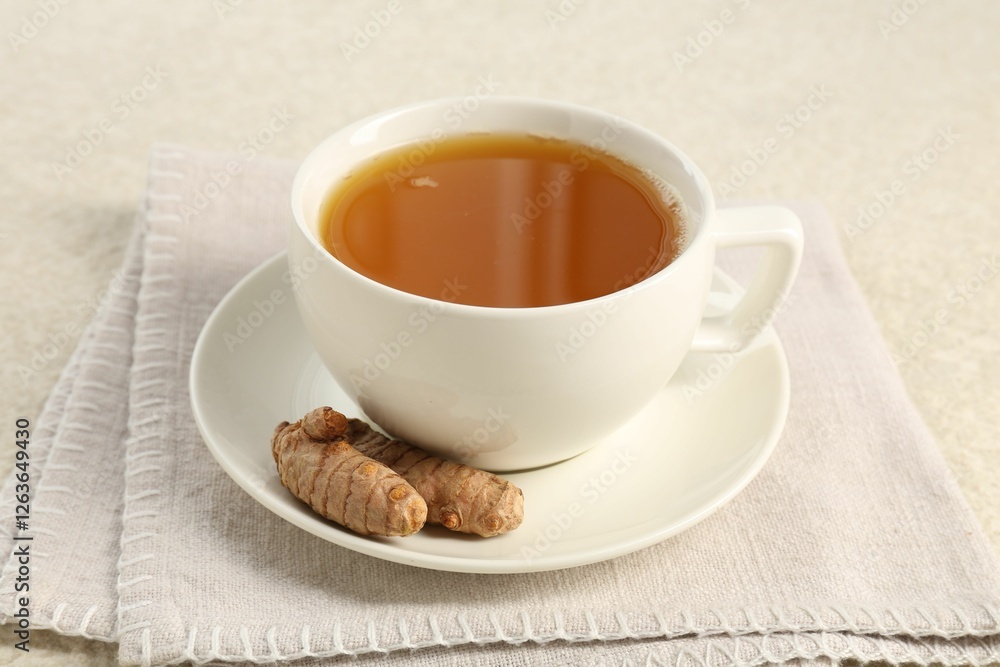 Aromatic turmeric tea and rhizomes on white textured table, closeup Aromatic turmeric tea and rhizomes on white textured table, closeup