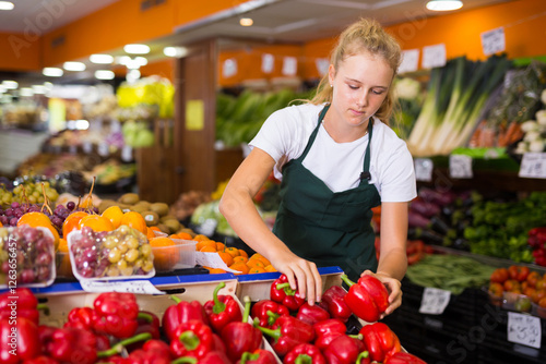 Fotografie Fifteen-year-old girl who works part-time in a store as a trainee saleswoman put
