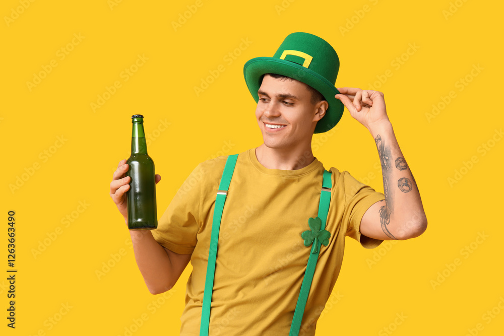 Happy young man in leprechaun's hat and with bottle of beer on yellow background. St. Patrick's Day Happy young man in leprechaun's hat and with bottle of beer on yellow background. St. Patrick's Day