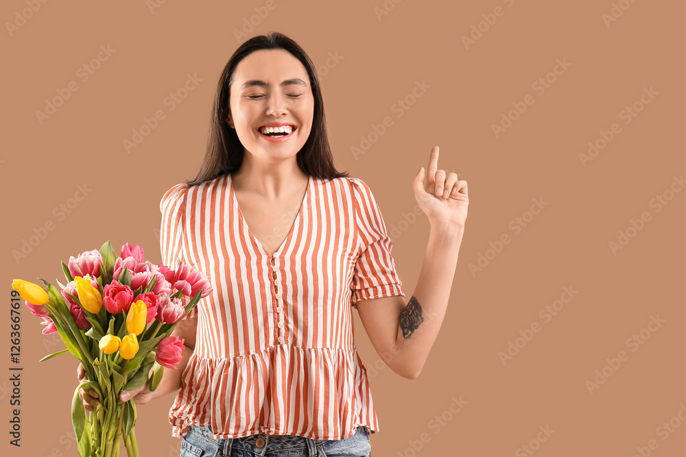 Happy young woman with bouquet of beautiful tulips pointing at something on brown background. International Women's Day Happy young woman with bouquet of beautiful tulips pointing at something on brown background. International Women's Day