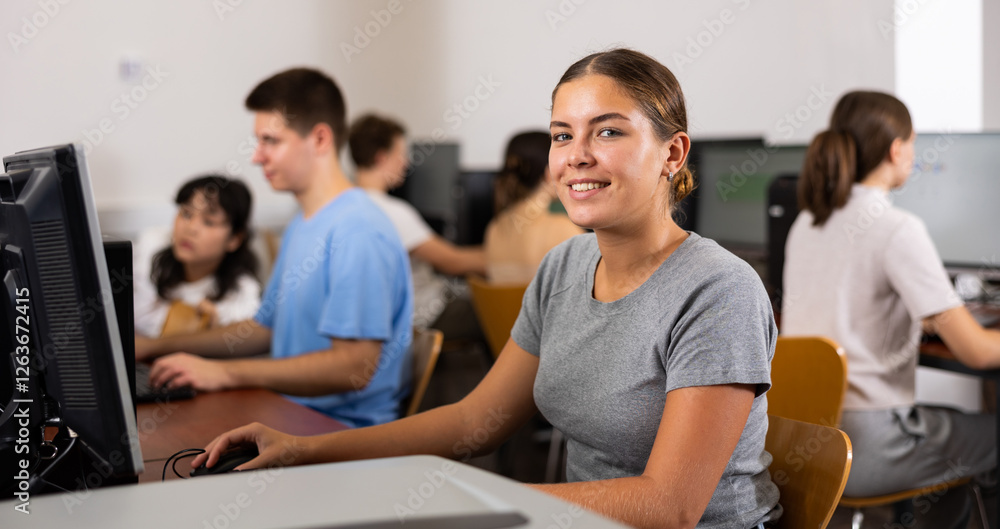 Smiling female student using PC and studying computer science in the classroom Smiling female student using PC and studying computer science in the classroom