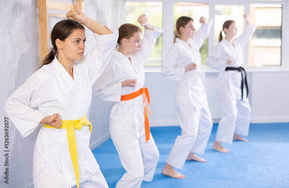 Group of teenage girls in kimono doing kata training in gym Group of teenage girls in kimono doing kata training in gym