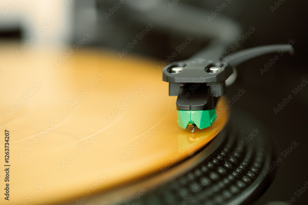 Giradischi, vista sulla testina. Disco musicale in vinile di colore giallo oro.