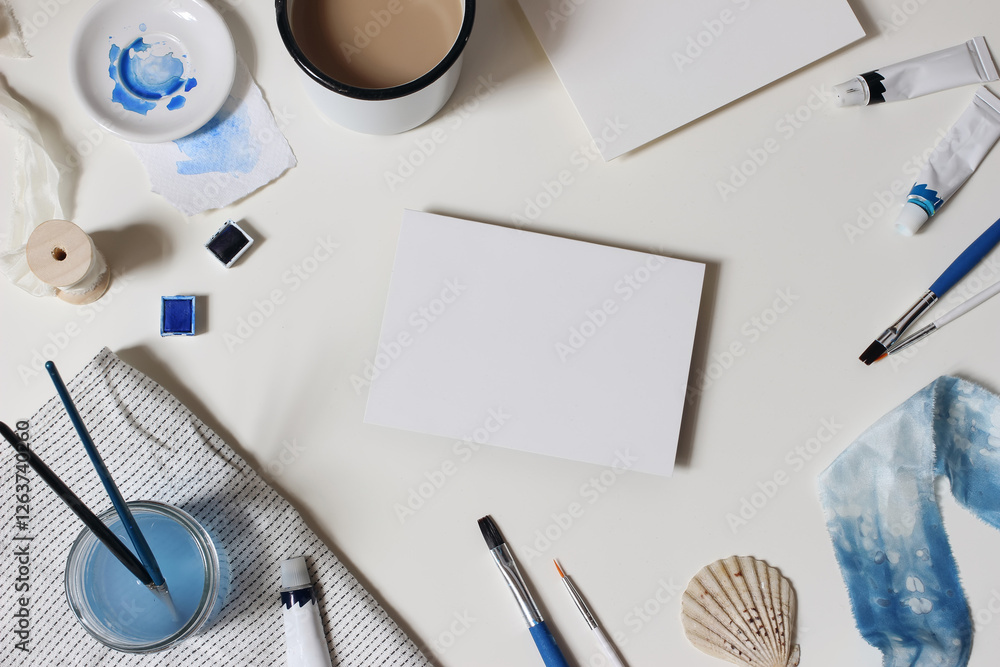 Fototapeta premium Watercolor, blue oil, acrylic color paint tubes. Brushes, palette. Cup of coffee. Blank paper card mockups isolated on white table. Art supplies. Creative background scene. Flat lay, top view