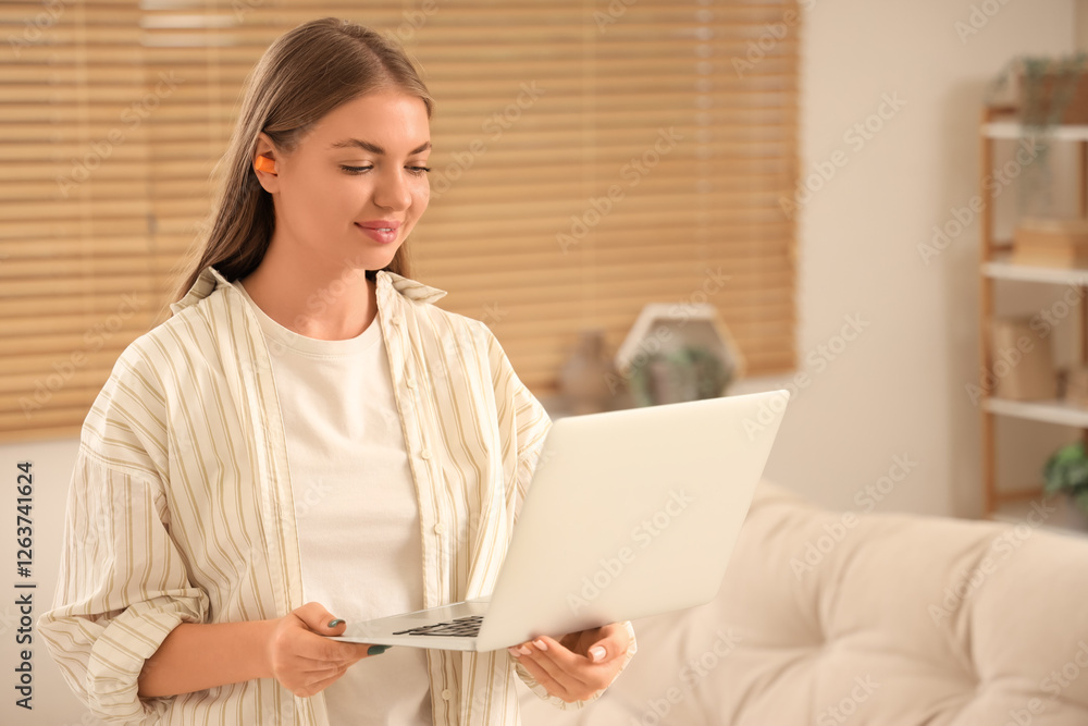 Young woman with earplugs and laptop at home Young woman with earplugs and laptop at home