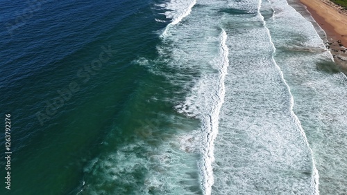 Drone shot aerial view of waves crashing onto the shore on a beach in summer in Australia 