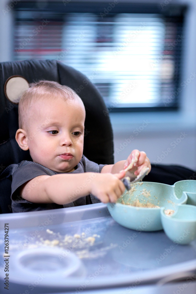 A little boy sits in a chair and eats porridge with his hands A little boy sits in a chair and eats porridge with his hands