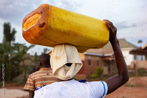 A woman carrying home a jerrycan full of water from a nearby water source. Rural Uganda.