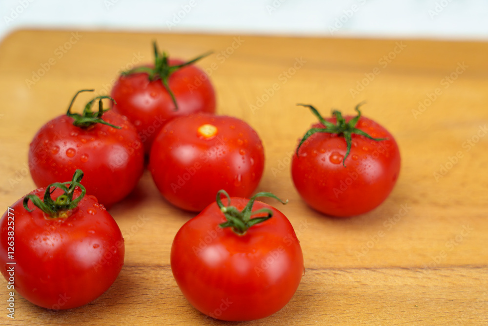 Fresh red tomatoes with water droplets on wooden cutting board Fresh red tomatoes with water droplets on wooden cutting board