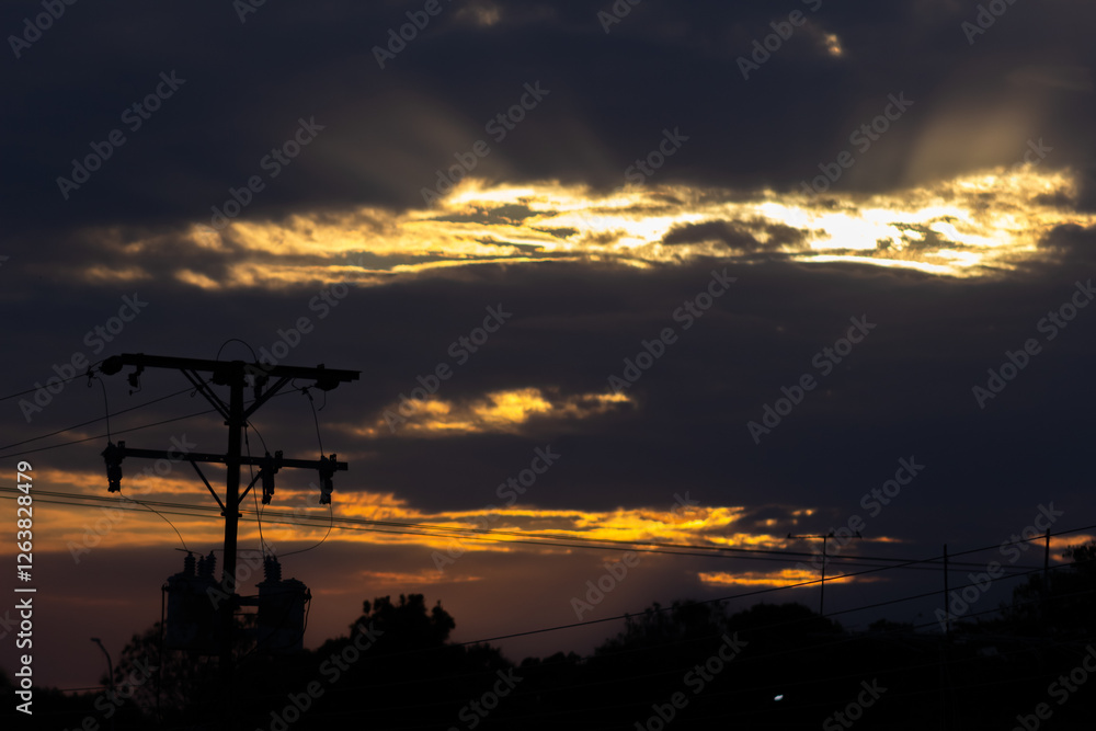 Fototapeta premium Beautiful sunset in the sky with clouds and electricity post. Landscape.