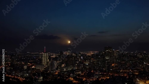 A time-lapse of a full moon rising over a city skyline, with lights gradually turning on as the evening sets in.