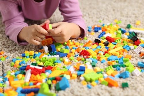 Girl playing with building blocks on floor at home, closeup