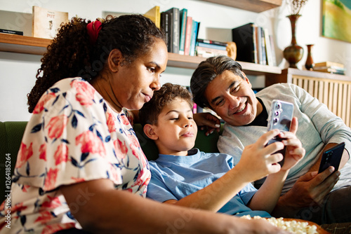 Portrait of a happy family relaxing together with smartphones at home photo