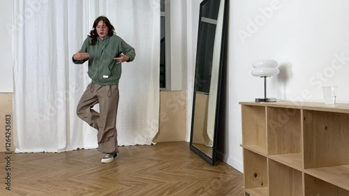 Dancer practices modern dance moves while facing a mirror in a spacious studio environment to enhance skills.