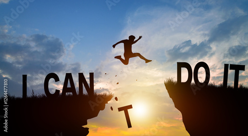 Silhouette man jumping over I can do it wording on cliffs with cloud sky and sunrise. Never give up, Good mindset, and Successful achievement Concept.