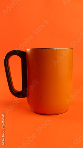 an orange cup whose paint has started to peel off, isolated in orange