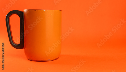 an orange cup whose paint has started to peel off, isolated in orange