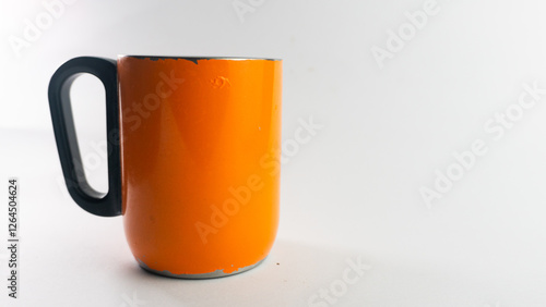 an orange cup whose paint has started to peel off, isolated on white