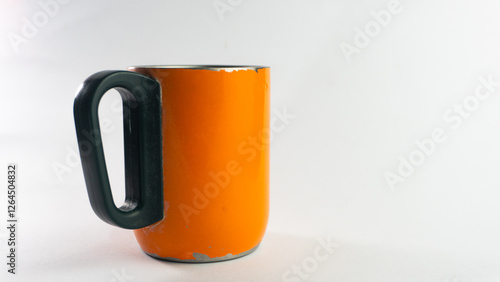 an orange cup whose paint has started to peel off, isolated on white