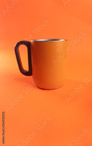 an orange cup whose paint has started to peel off, isolated in orange