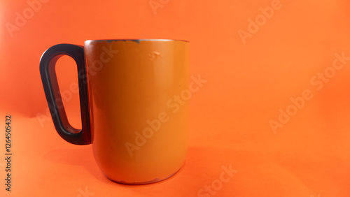 an orange cup whose paint has started to peel off, isolated in orange
