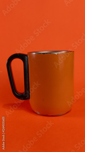 an orange cup whose paint has started to peel off, isolated in orange