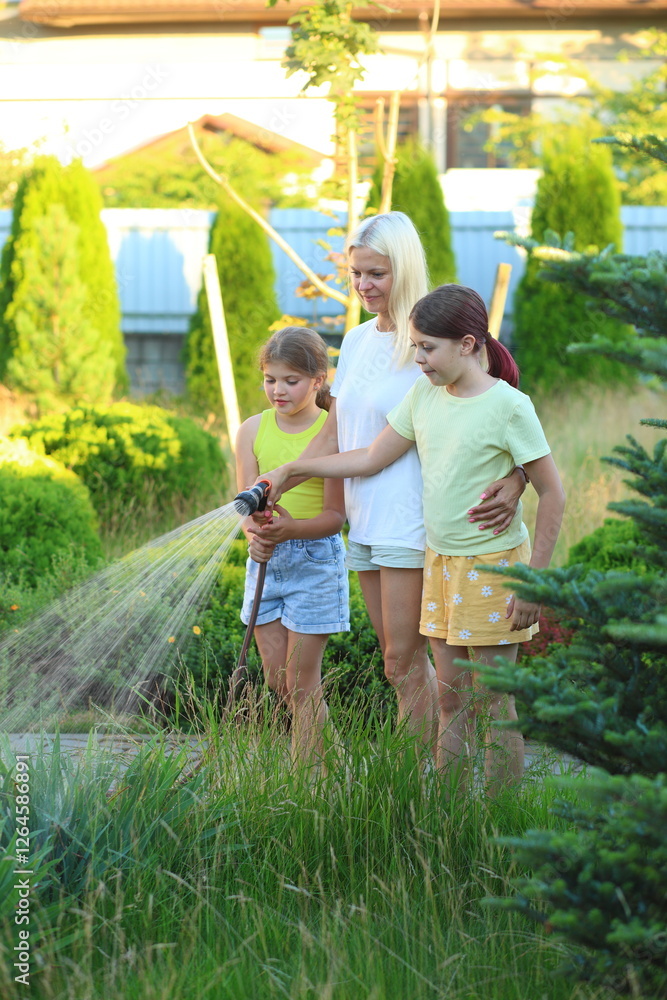 © Nadya Kolobova - Mother and Children Using Drip Irrigation to Water Flowers. a mother and her two children watering flowers in their garden using a drip irrigation hose. they enjoy the process of nurturing