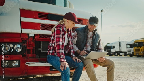 Wallpaper Mural Front camera view of Caucasian husband and wife resting on front bumper of their truck. Looking at laptop screen while searching for information. Solving issue together as team. Supporting. Torontodigital.ca
