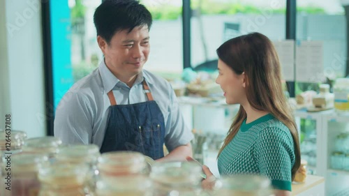 Eco friendly store owner talking to client and advising customer bio organic goods product in plastic free zero waste grocery shop. Sustainable small local business SME startup go green market.
