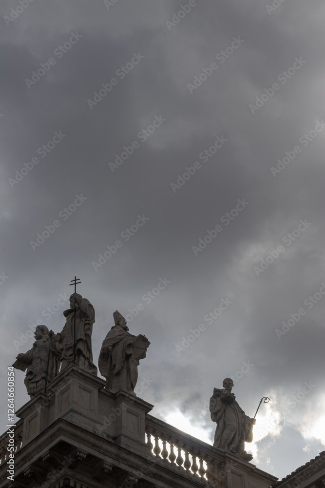 Fototapeta premium Statues on a Historic Building with Dramatic Cloudy Sky Backdrop, Basilica di San Giovanni in Laterano