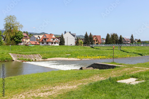 NOWY TARG, POLAND - MAY 27, 2023: Boulevards on the Dunajec River in Nowy Targ. Charming estates of single-family houses right by the water. photo