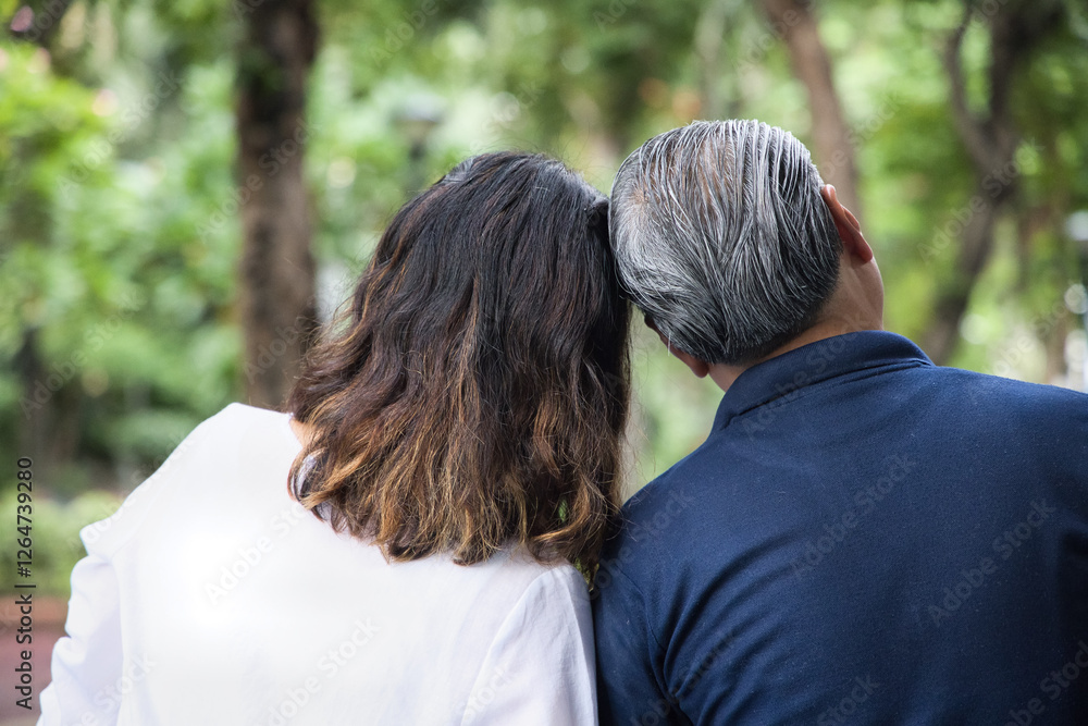 Lovely couple of Asian husband and wife, Happy Asian family with middle-aged spouse married couple staying together in outdoor green park, concept of Happy Family Day and Togetherness, Back rear view Lovely couple of Asian husband and wife, Happy Asian family with middle-aged spouse married couple staying together in outdoor green park, concept of Happy Family Day and Togetherness, Back rear view